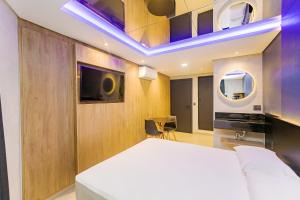 1 dormitorio con 1 cama blanca y TV en Drops Express Motel Curitiba, en Curitiba