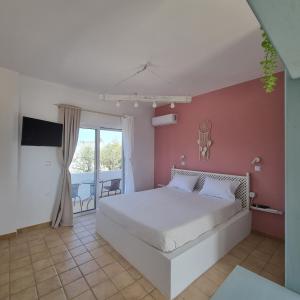 een slaapkamer met een wit bed en een balkon bij Arocaria - Faliraki peaceful apartments in Faliraki
