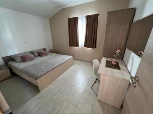 a small bedroom with a bed and a table at Apartmani Nina i Niko in Ugljan