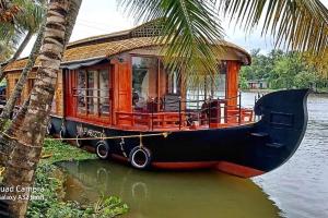 a house boat on the water next to a palm tree at Grand Villa Houseboat in Kumarakom