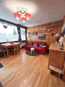 a living room with a red couch and a table at Casetta dei Cuori - Alpine Style Cozy Apartment in Folgarida