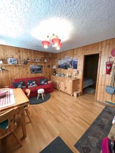 a living room with a red couch and wooden walls at Casetta dei Cuori - Alpine Style Cozy Apartment in Folgarida