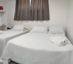 2 camas en un dormitorio con sábanas blancas y toallas en Cabanos Suites, en Maragogi
