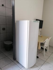um frigorífico branco num quarto com uma secretária em quarto para Rapaz, centro, Sinop MT em Sinop