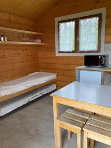 una habitación con 2 camas y una mesa en una cabaña en Camping Sérendipité, en Neuvéglise