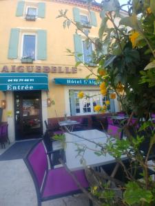 un restaurante con sillas moradas frente a un edificio en L'Aiguebelle, en Céreste