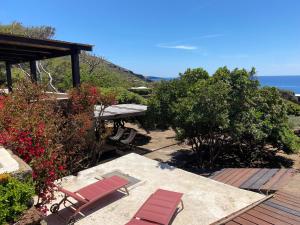 a patio with two chairs and a picnic table and the ocean at Dammuso Tuffo nel mare in Pantelleria