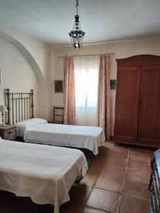una camera con due letti e un lampadario a braccio di Casa de campo - Cortijo El Palomar a Alcántara