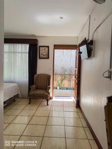 Zimmer mit einem Bett, einem Stuhl und einem Fenster in der Unterkunft Casa Mariana in Alajuela
