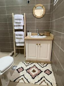 a bathroom with a sink and a toilet and a rug at Maison d H&ocirc;te Ighrem in Goulmima