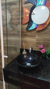 un lavabo negro en un baño con una pintura en la pared en Cabanos Suites, en Maragogi