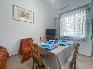 a dining room with a table and chairs and a television at Aquaterra Askeli Poros in Poros