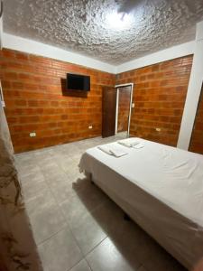 a bedroom with a bed and a tv on a brick wall at Departamento temporario ROSARIO in Formosa