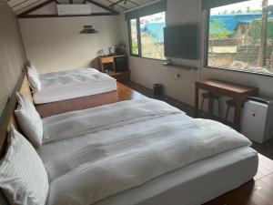 a bedroom with two beds and a table and a window at Jiang's B&B 江院子庭園民宿 in Ji'an