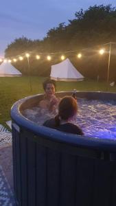 2 filles dans un bain à remous lors d'une fête dans l'établissement Luna Tent Secret garden Glamping, 