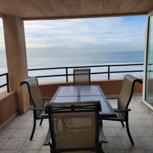 una mesa y sillas en un balcón con vistas al océano en Oceanfront Condominiums with Private Beach Access en Tijuana