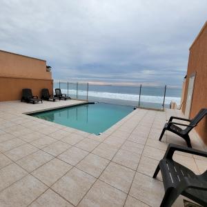 una piscina con sillas y el océano en el fondo en Oceanfront Condominiums with Private Beach Access, en Tijuana