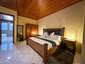 um quarto com uma cama grande e um tecto de madeira em The Haven Boutique Hotel em Kumasi