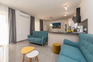 uma sala de estar com duas cadeiras azuis e uma cozinha em Villa Mattina, with heated pool and jacuzzi em Privlaka