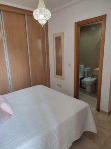 a bedroom with a white bed and a chandelier at Mojacar a in Mojácar