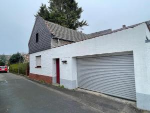 ein weißes Gebäude mit einer Garagentür neben einer Straße in der Unterkunft Bollgarten 8 in Köln