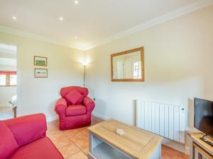 a living room with a red chair and a tv at Orchard Cottage in Saint Osyth