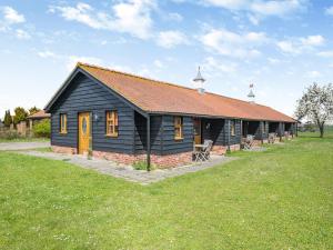 a small black building with a red roof at Orchard Cottage in Saint Osyth