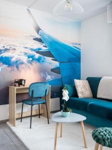 a living room with a blue couch and a painting of an airplane at In the Sky - Casa Vostra - Ambilly proche tramway - frontière in Ambilly