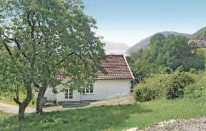 una casa blanca en un campo con un árbol en Amazing Home In Lyngdal With Kitchen, en Lyngdal