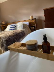 bandeja de madera en una cama con una botella de jabón en Cosy cottage and lodge, near York, 