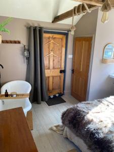 1 dormitorio con baño y puerta de madera en Cosy cottage and lodge, near York, 