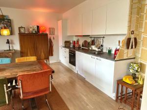 cocina con armarios blancos y mesa de madera en 2 værelses retro lejlighed på Torvet en Horsens