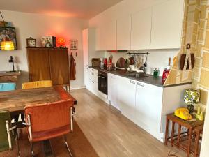 a kitchen with white cabinets and a wooden table at 2 værelses retro lejlighed på Torvet in Horsens
