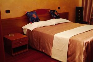 a hotel room with a bed and a night stand at Hotel Bengasi in Moncalieri