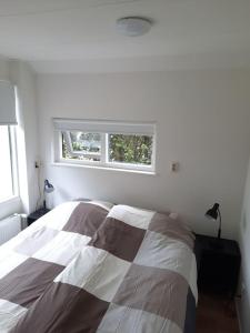 Habitación blanca con cama y ventana en 4-6 persoons vakantiewoning met eigen tuin en Bakkeveen