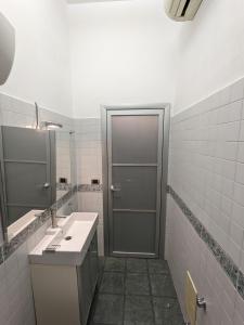 ein Badezimmer mit einer Tür, einem Waschbecken und einem Spiegel in der Unterkunft Napoli City Panorama in Neapel
