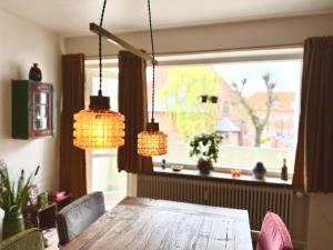 a dining room table with two chandeliers and a window at 2 værelses retro lejlighed på Torvet in Horsens