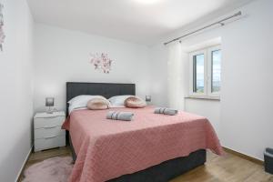 a bedroom with a large bed with a pink blanket at Apartment Ivana in Malinska