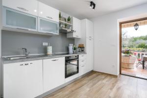 a kitchen with white cabinets and a large window at Apartment Ivana in Malinska