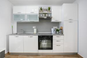 a white kitchen with white cabinets and a sink at Apartment Ivana in Malinska