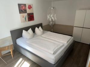 1 cama con sábanas blancas y almohadas en una habitación en Apartment Stabel 8,1 km von Europa Park, en Kippenheim