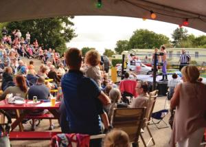 a crowd of people sitting at tables in a crowd at Parc Farm Holiday Park in Mold