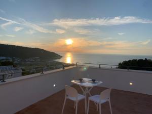 een balkon met een tafel en 2 stoelen en de zonsondergang bij Thai Boutique rooms in Peschici