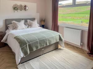 a bedroom with a bed and a large window at Mossdale Cottage in Dalmellington