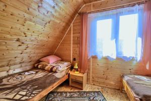 Dormitorio en cabaña de madera con litera y ventana en Domki Zacisze nad wodą en Baligród