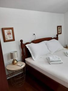 a bed with white sheets and a night stand with a lamp at Apartments Iva in Kotor