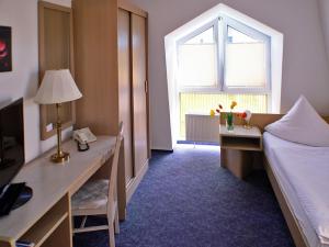 um quarto com uma secretária, uma cama e uma janela em Hotel Fürstenberg em Eisenhüttenstadt