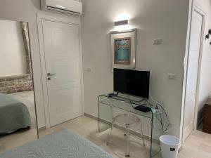 a room with a tv on a glass table and a door at Suite Duomo Trani 8 in Trani