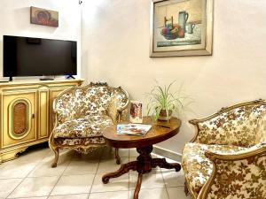 a living room with two chairs and a table and a tv at Dimora delle Mura in San Quirico dʼOrcia