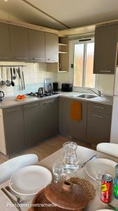 una cocina con una mesa con copas de vino. en Les mobil homes de NOLY Draps inclus ,TV ,Clim en Port-la-Nouvelle